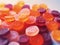 Close-up texture of red, orange and purple multivitamin gummies on white background