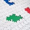 Close-up texture of a white jigsaw puzzle in assembled condition with missing elements, under which surfaces of different colors