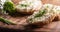 Close up of a thick spread of sheep cheese on slices of bread with finely chopped chives on top