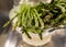 Close up of thin asparagus resting on white colander after being washed