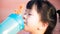 Close up of thirsty girl drinking clean water. Cute kid holding a blue bottle of water.