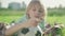 Close-up of thoughtful blond boy with green eyes lying on green meadow with soccer ball. Portrait of cute little