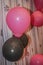 Close up of three colors balloons i.e.Black with danger sign,white and pink on a fabric.Concepts of celebrating every moment of