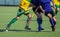 Close up of three field hockey players, challenging eachother for the control and posession of the ball during an intense, competi