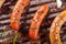 Close up of three grilling sausages on barbecue grill with some species. BBQ in the garden. Bavarian sausages