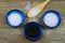 Close up of three isolated blue bowls with different kind of salt on wood table with spoon white flakes and grains, black Hawaii