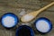 Close up of three isolated blue bowls with different kind of salt on wood table with spoon white flakes and grains, black Hawaii