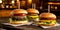 Close-up of three juicy cheeseburgers on a wooden table on a kitchen board against a background of a blurred rustic