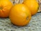 Close up of three juicy orange yellow oranges on rattan cane bamboo handmade woven works background.