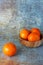 Close up of three mandarin on wooden bowl, with selective focus on vertical worn surface