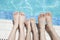 Close up of three people\'s legs by the pool side