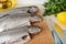 Close-up of three raw gutted trout fishes on a wood cutting board prepared for cooking. Fresh fish dishes, healthy eating and cook