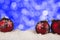 Close up on three red bauble, blue bokeh lights in background.