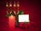 Close-up of three red roses, two glasses of champagne and a lit red candle on a red background in honor of Valentine`s