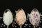 Close-up of three silver teaspoons that lie in front of a black background and in which various salt mixtures and salt crystals