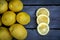 Close up of Three slices of  lemon arranged with a group of lemons sitting on a wood table