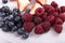 Close-up of three small bowls overflowing with summer berries, strawberries, raspberries, blueberries