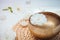 Close up Tibetan singing bowl with floating in water rose inside. Burning candles, flowers petals on the white wooden background.