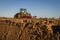 Close up of tilled soil with tractor diffused in background