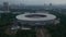 Close up tilting aerial shot of Gelora Bung Karno athletic stadium facilities in modern city center of Jakarta