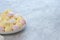 Close-up tiny meringues of pink, white and yellow colors in a white bowl over white light gray table. Sweet dessert