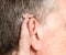 Close up of a tiny modern hearing aid behind ear