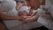Close-up tiny newborn baby feet in female hand with happy man kissing little toes in slow motion smiling. Excited