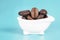 Close-up of a tiny white bathtub full of roasted coffee beans on a light blue background.