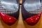 Close up of the tip of a pair of shoes with a combination of black, red and white on a parquet floor