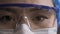 Close up of tired doctor eyes. Woman in protective glasses, mask and cap looks at camera. Medical worker exhausted by