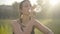 Close-up of tired woman drinking water in sunrays. Portrait of exhausted Caucasian sportswoman refreshing after workout