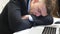 Close up to exhausted boss in formal suit falling asleep on table at office. Young entrepreneur sleeping on desk with