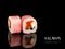 Close up to sushi roll pieces with mirror reflection on black background. Sushi roll with salmon, flying fish roe and rice paper