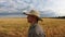 Close up to young agronomist walking among ripe wheat meadow at overcast summer day. Male farmer going through the