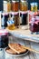 A close up of toast and raspberry jam with jars of jam and honey in crisp focus in behind.