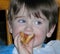 Close up of toddler boy with very blue eyes eating pizza