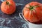 Close-up of a tomato in metal bucket on bluish marble background with another tomato out of focus in the background