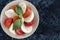 close-up of tomato and mozzarella circles with basil leaf. serving of Italian caprese salad. flat lay. Soft focus.