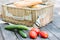 Close up of tomatoes and cucumbers over wooden table in front of an open picnic basket.