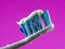 Close-up toothbrush and toothpaste with drops and purple background