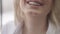 Close-up toothy smile of young slim charming Caucasian blond woman. Unrecognizable positive millennial smiling having