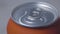 Close-up of the top of closed orange can. Metal container with carbonated soft drink or alcohol. Beverage, liquid.