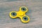 Close up top high angle above view photo of bright yellow fidget spinner isolated on wooden grey background style stylish modern t