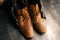 Close-up top view of hands of shoemaker shoemaker in black gloves holding old worn light brown leather shoes