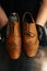 Close-up top view of hands of shoemaker shoemaker in black gloves holding old worn light brown leather shoes