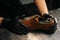 Close-up top view of hands of shoemaker shoemaker wearing black gloves inserts wooden shoe pad into worn light brown