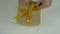 Close up top view high angle. Mens hands straighten a gold bow from a satin ribbon on a gift box. Preparing for the gift