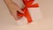 Close up top view high angle. Mens hands straighten a red bow from a satin ribbon on a gift box. Preparing for the gift