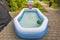 Close-up top view of inflatable children\\\'s pool with water on front yard in garden of villa.