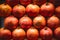 Close up, top view. Ripe red pomegranates are neatly laid out in rows on the counter at a Spanish bazaar